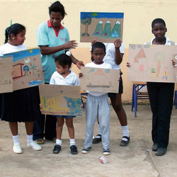 Kinder aus Ecuador zeigen in ihrem Klassenraum selbstgemalte Bilder.