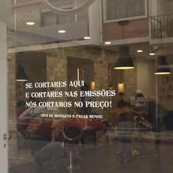 Aufschrift auf dem Schaufenster: „Ihr kommt mit dem Rad zu uns und senkt damit die Emissionen, dann senken wir den Preis Eures Haarschnitts“