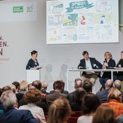 Mehrere Personen sitzen auf einem Podium