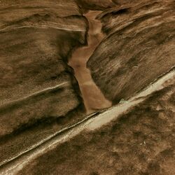 Schmelzwasser läuft eine kleine Rinne entlang.