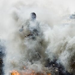 Mensch in Rauchschwaden bei der Verbrennung von Schrott.