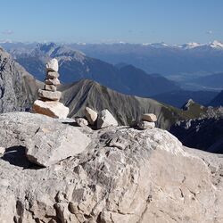 Aufgetürmte Steine im Vordergrund; Panoramablick über die Zugspitze im Hintergrund