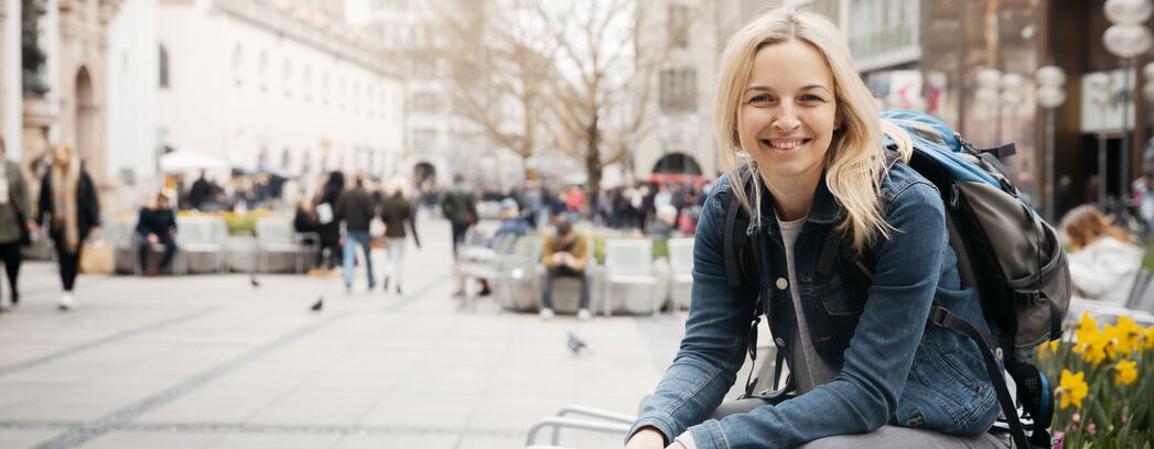 eine Frau sitzt in einer Fußgängerzone und lächelt in die Kamera