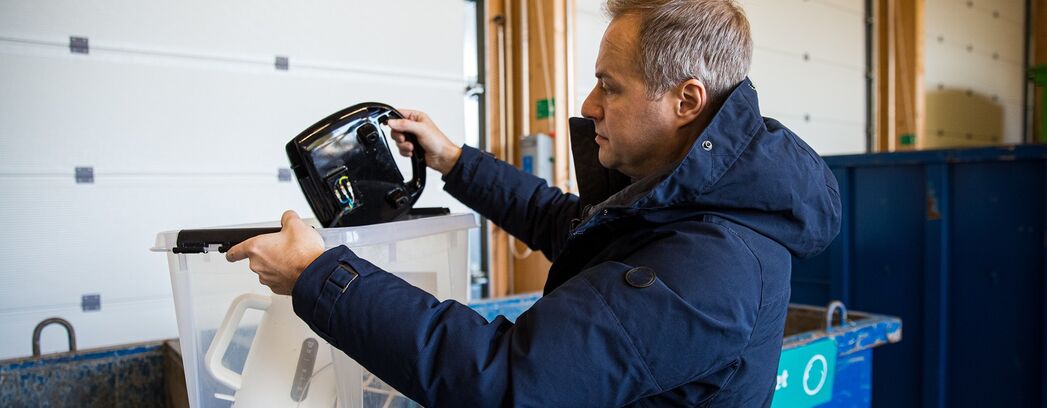 Mann entsorgt Elektroschrott in einen Container