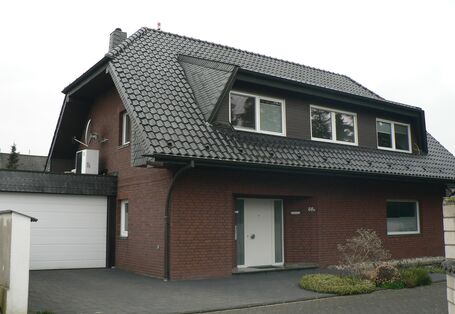 Ein Einfamilienhaus mit angebauter Garage mit Wärmepumpe auf dem Dach.