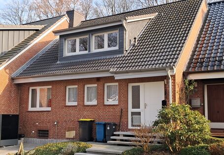 Straßenansicht des geklinkerten Reihenmittelhauses mit Dachgaube auf dem schwarzen Dach