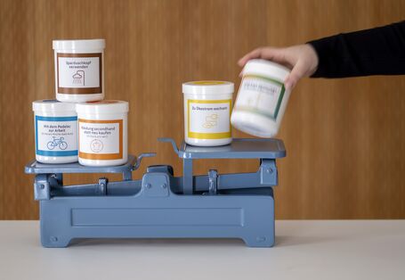 Die Klimawaage zeigt spielerisch anhand verschiedener, beschrifteter Dosen, die gegeneinander abgewogen werden können,, wie Alltagsentscheidungen das Klima beeinflussen.