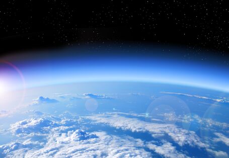 Ein Ausschnitt des Planeten Erde wird so dargestellt, dass man die Krümmung der Erde erkennt. Die Atmosphäre hat einen leichten blauen Leuchtrand.