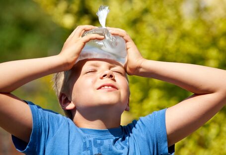 Das Foto zeigt ein Kind, das sich mit beiden Händen einen Eisbeutel zur Kühlung an die Stirn hält.