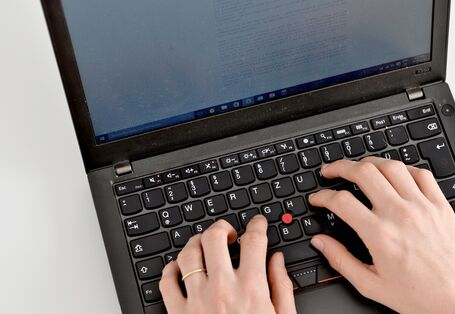 Eine Person tippt auf einer Laptop-Tastatur.