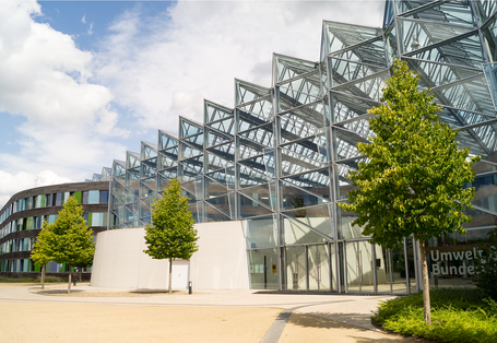 modernes Bürogebäude mit viel Glas, davor Bäume, am Eingang Schriftzug Umweltbundesamt