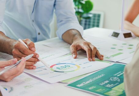 Vier Menschen sitzen an einem Tisch und sprechen über Statistiken aus dem Klimamanagement ihres Unternehmens