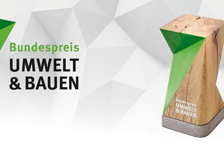Banner mit Logo, Trophäe und Bewerbungsaufruf. Das Logo zeigt in drei Zeilen die Worte "Bundespreis, UMWELT, & BAUEN". An der linken oberen Ecke ein aufwärtszeigender Pfeil, der aus zwei grünen Dreiecken zusammengesetzt ist. Die Trophäe ist ein stehender Abschnitt eines Holzbalkens auf einem flachen Betonsockel. Die Ansichtsfläche ist angeschnitten, die Schnittflächen sind grün gefärbt, sodass sich der Pfeil des Bundespreislogos ergibt. Darunter die Wortmarke "Bundespreis UMWELT & BAUEN". Der Bewerbungsaufr