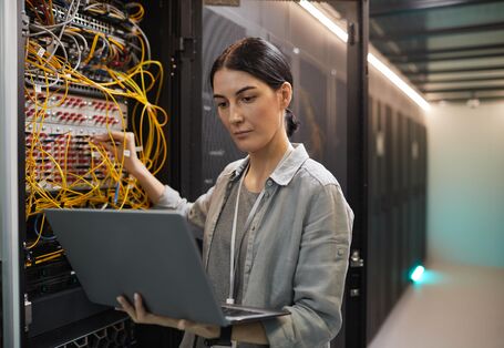 Eine Ingeneurin steht vor einem Server.