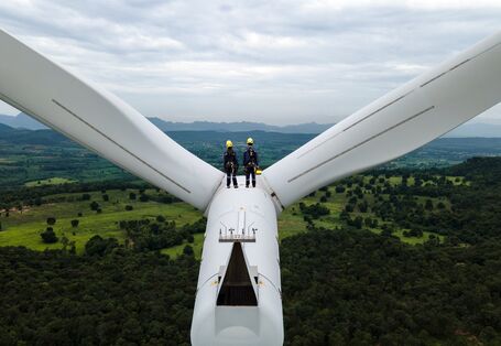 Two people standing on a wind turbine.