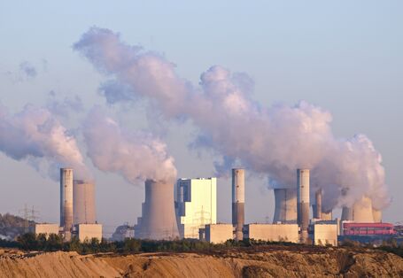 Das Bild zeigt rauchende Schornsteine von Industrieanlagen.