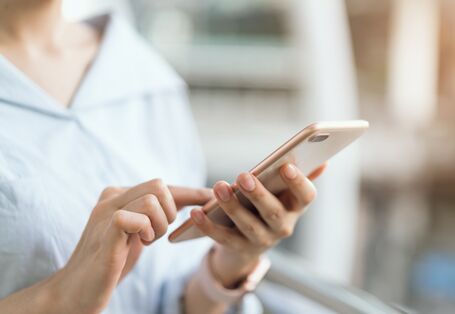 Eine Frau hält ein Smartphone in der Hand.