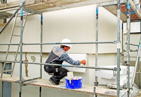 Ein Handwerker bringt Dämmung an einer Hausfassade an.