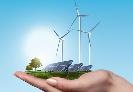 Hand hält Solarfeld und Windräder