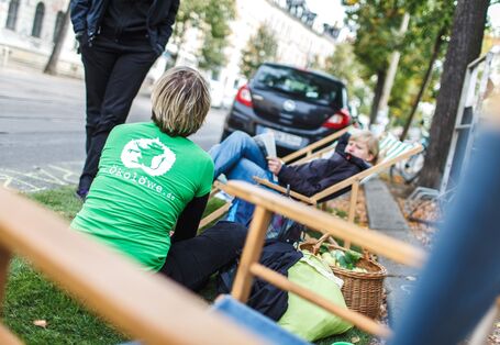Menschen rasten auf Parkplatz an Straßenrand mit Sonnenliegen