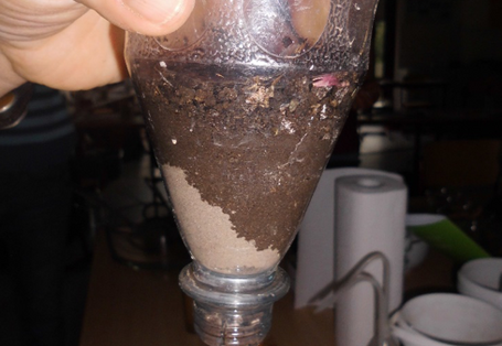 Wasser befeuchtet sandigen Boden im Trichter – wird alles gleich unten herausströmen oder nicht?