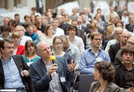 Ein Mann aus dem Publikum hält ein Mikrofon und spricht
