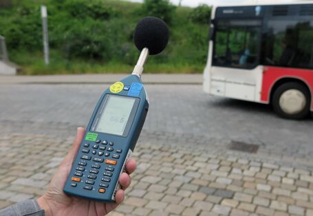 Ein vorbeifahrender Omnibus wird mittels Handschallpegelmessgerät akustisch gemessen
