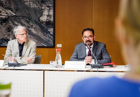 Das Bild zeigt Christian Kühn, den Parlamentarischen Staatssekretär des Bundesministeriums für Umwelt, Naturschutz, nukleare Sicherheit und Verbraucherschutz . Dieser sitzt an einem Tisch und begrüßt die Jury