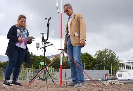 Eine Frau und ein Mann nehmen Daten eines Messgerätes auf einem Flachdach