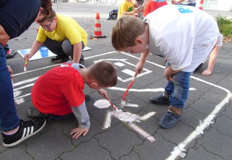 Kinder malen ihr Verkehrszeichen auf den Boden