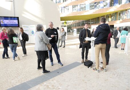 Small groups of people are standing at high tables in the atrium of the german federal environment agency.