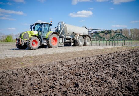 Foto: Ackerfläche mit Traktor und Schleppschlauchapplikator.