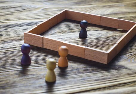 A token stands in the middle of a wooden square, three others stand outside.