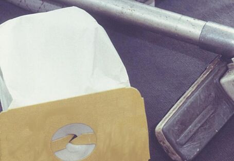 Stausaugerbeutel liegt neben einem Staubsauger