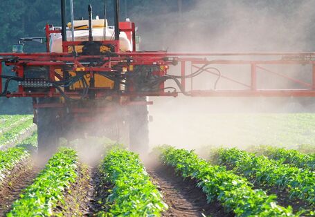 Das Bild zeigt eine Pflanzenschutzspritze, die übers Feld fährt.