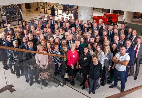 Blick von einer Treppe in eine Empfangshalle, dort stehen ca. 60 Personen nebeneinander mit Blick zur Kamera.