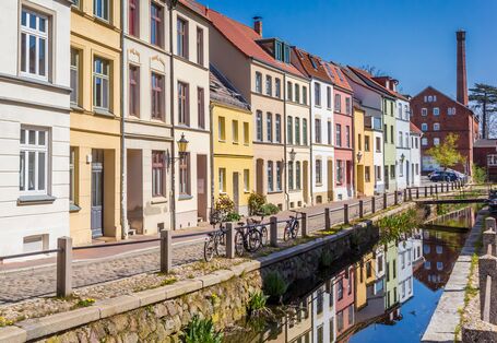 Das Bild zeigt innerstädtischen Gebäudebestand und abgestellte Fahrräder entlang eines Gewässers.