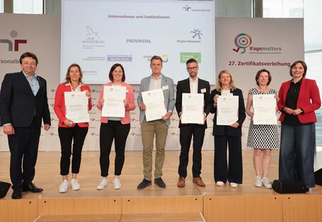 Gruppenfoto mit den Zertifikaten auf einer Bühne 