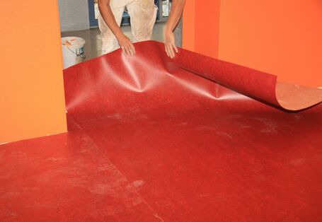 Handwerker verlegt einen roten Fußbodenbelag