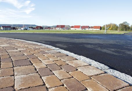 asphaltic street and paved footway, in the background new houses