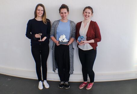 drei junge Frauen mit Trophäen lehnen an einer Wand