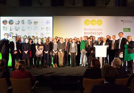 Vor einer Stellwand mit dem Logo des Bundespreis Ecodesign stehen die Preisträger