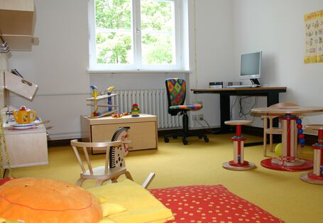 Zimmer mit Kinderbett, Spielzeug und einem Schreibtisch mit Computer für Erwachsene