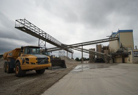 Foto einer Industrieanlage, davor zerkleinertes Gestein und ein Muldenkipper