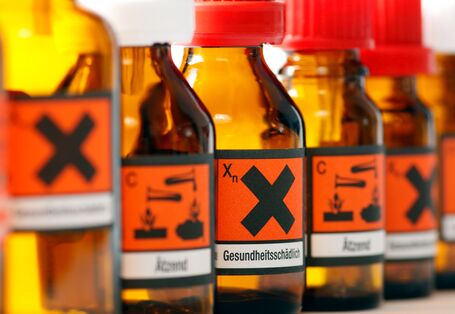 Glasfläschchen mit Warnhinweisen wie "ätzend" und "gesundheitsschädlich".