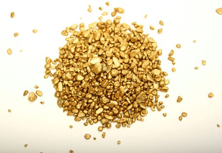 ein kleines Häufchen Goldklumpen auf einer weißen Unterlage