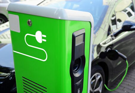 ein Elektroauto tankt Strom an einer grünen Ladesäule