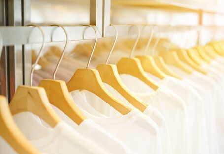 in einem Geschäft hängen viele weiße T-Shirts auf Bügeln an einer Stange