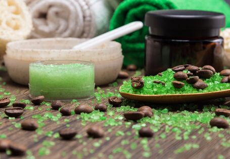 Kosmetiktiegel und Handtücher mit grünen Kügelchen und Kaffebohnen auf einer Holzoberfläche arrangiert