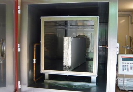 in einem großen Stahlbehälter mit Tür steht ein Bauprodukt, daneben ein elektronische Gerät zur Durchführung einer Emissionsmessung